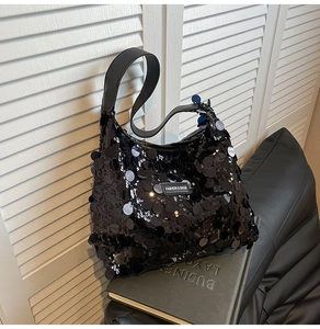 Detail of black sequin tote bag showing shimmering texture and fashion label