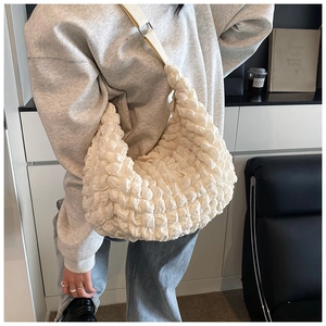Close-up of beige puff shoulder bag with 3D popcorn texture and wide woven strap