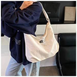 Dettaglio della grande borsa hobo in tela bianca con tracolla regolabile ed etichetta