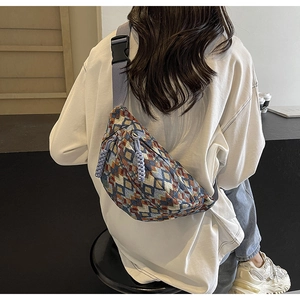 Close-up of geometric woven chest bag with wide blue strap and patterned fabric detail