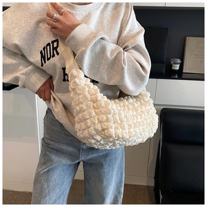 Detailed macro view of the cream-colored bubble texture fabric on a crescent shoulder bag
