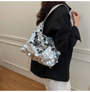 Detail of silver sequin tote bag with wide strap and fashion brand metal plaque