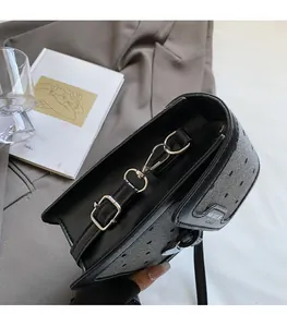 Détail du mini sac bandoulière noir avec rabat texturé et boucle métallique argentée