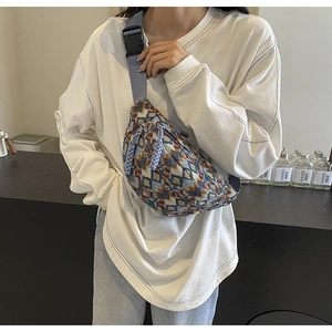 Close-up of knit geometric chest bag featuring blue woven strap and buckle closure
