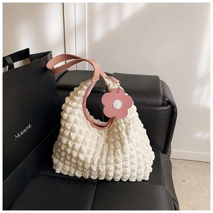 Détail du sac cabas gaufré blanc avec anses en cuir rose et breloque fleurie