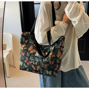 Detail of floral canvas tote bag with butterfly print shown on shoulder with wide straps