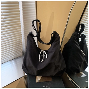 Dettaglio borsa hobo in tela nera con tracolla regolabile ed etichetta moda su sfondo d'arte