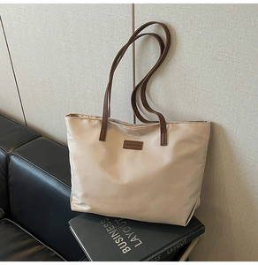 Close-up of beige nylon tote bag with leather straps and Fashion & Bags brand patch