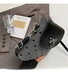 Detailed view of grey polka dot crossbody bag with a silver bow clasp and leather flap