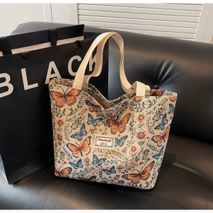 Close-up of beige tote bag with colorful butterfly and floral embroidery detail