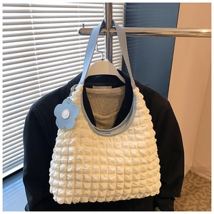 Détail du sac cabas gaufré blanc avec bandoulière en cuir bleu clair et pendentif fleurie