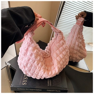 Detail of pink puff shoulder bag with waffle pleated texture on a mirror surface