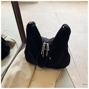 Dettaglio della borsa in tela nera con tiranti in corda intrecciata e logo moda