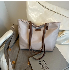 Close-up of light purple tote bag with brown leather straps and fashion label detail