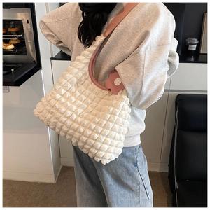 Détail du sac cabas gaufré blanc avec bandoulière en cuir rose et breloque fleur