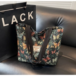 Detail of floral butterfly print on vintage tote bag with woven brand label and black strap