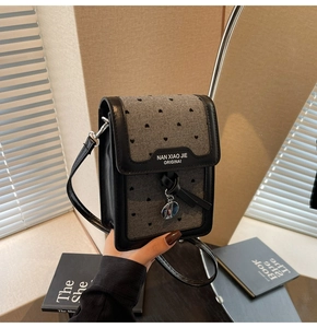 Détail d'un sac téléphone à motif cœurs avec lettrage original et pendentif doré