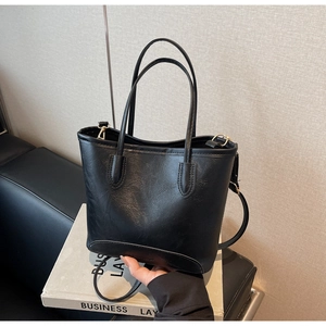 Close-up of black PU leather tote bag with fine litchi grain and gold hardware accents