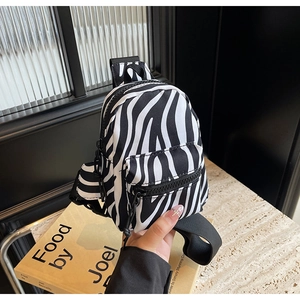 Detailed view of mini zebra print shoulder bag with black metal zipper and canvas texture