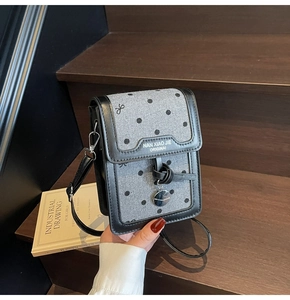Détail du mini sac à portable en laine grise avec pois noirs et pendentif en métal