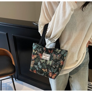 Close-up of colorful butterfly floral tote bag with branded woven label and handles