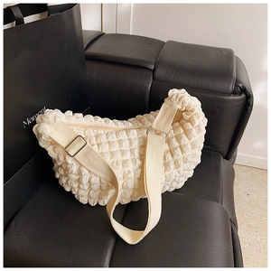 Detailed view of cream bubble texture crossbody bag with adjustable wide strap on black leather