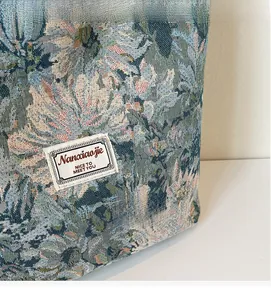 Detailed macro shot of vintage floral jacquard fabric and brand label on a tote bag