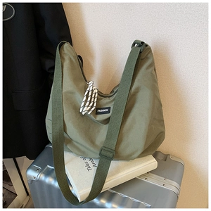 Dettaglio della borsa a tracolla in nylon verde militare con etichetta su valigia