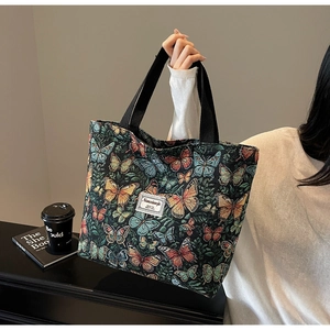 Detailed macro view of the colorful butterfly jacquard fabric on the black tote bag