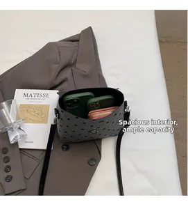 Spacious interior of grey polka dot felt crossbody bag holding phones and a wallet