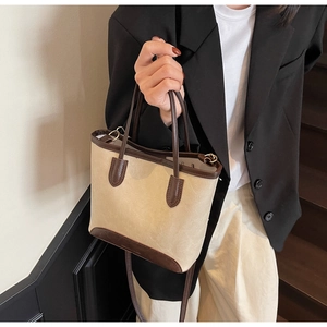 Detail of a vintage contrast leather tote bag showing beige texture and brown straps