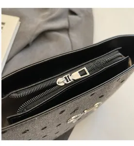 Detailed close-up of smooth silver metal zipper on black polka dot handbag