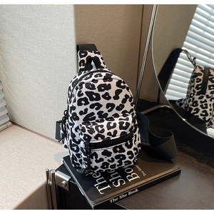 Detailed view of leopard print mini chest bag on black books with mirror reflection