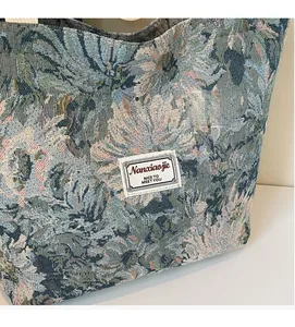Close-up of jacquard floral tote bag featuring a white woven label and grey-blue fabric