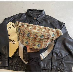 Close-up of vintage multi-color woven chest bag with beige strap on a leather jacket