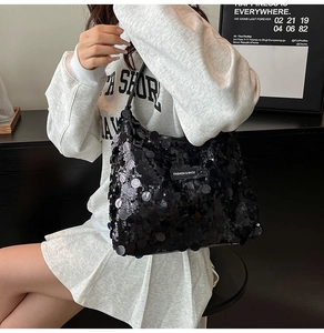 Detail of a chic black sequin tote bag shown as a shoulder bag on a model in gray outfit