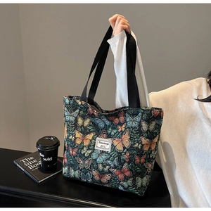 Close-up of jacquard floral tote bag featuring colorful butterfly patterns and black straps
