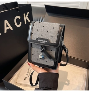 Détail du sac de téléphone en tweed gris avec broderie cœur et pendentif ruban chic