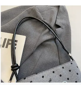 Close-up of gray polka dot canvas handbag with knot strap and soft wool-like texture