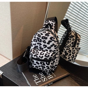 Detail of leopard print chest bag with black adjustable strap and dual zipper pockets