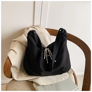 Dettaglio di una grande borsa tote in tela nera con coulisse a righe su sedia di legno
