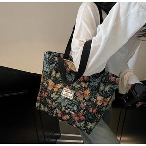 Detail of floral tote bag with colorful butterfly embroidery and black shoulder strap