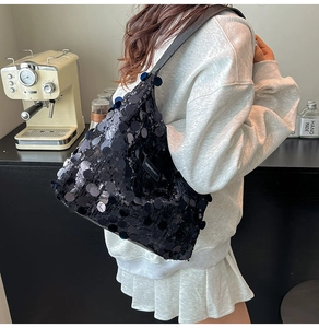 Detail of black sequin hobo bag showing large round sequins and wide shoulder strap