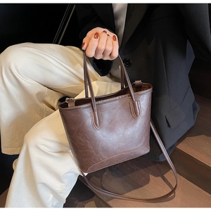 Detail of dark brown vintage faux leather tote with textured finish and brand logo