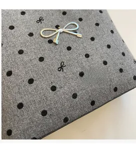 Macro shot of grey polka dot canvas bag featuring a polished silver metal bow detail