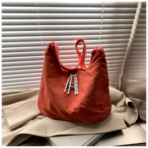 Dettaglio della borsa hobo in tela terracotta con etichetta moda su blazer beige