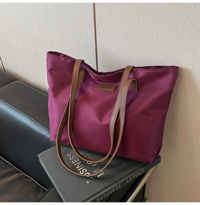 Macro detail of dark burgundy nylon tote bag with brown leather straps and fashion label