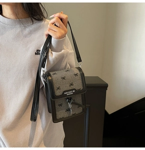 Vue détaillée de la texture gaufrée grise et des motifs de nœuds noirs sur le mini sac