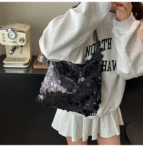 Detailed view of black sequined tote bag with a fashion logo patch on casual shoulder strap