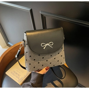 Détail d'un sac à bandoulière à pois avec boucle nœud en argent et rabat noir élégant
